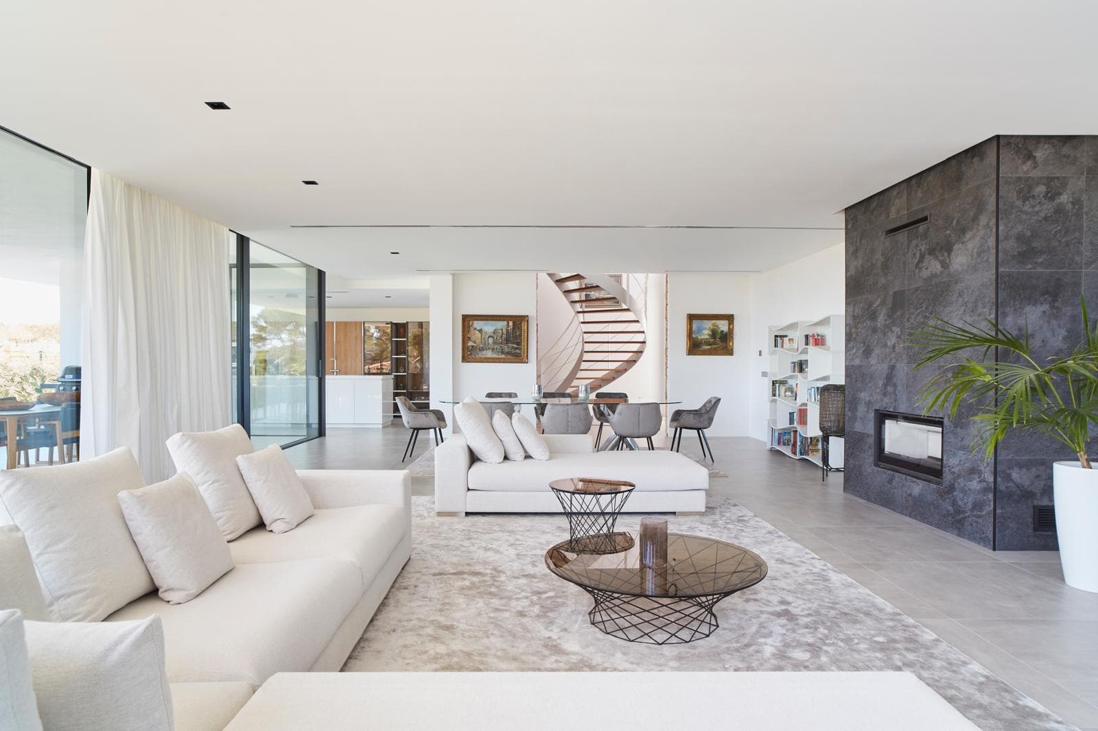 White living room with a stone fireplace and glazing to the terrace at Villa Lucero, Cala Salada, Ibiza