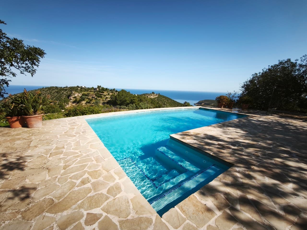 Infinity pool on a stone terrace looking out across the valley to the sea at Can Delfin, Sant Llorenc de Balafia